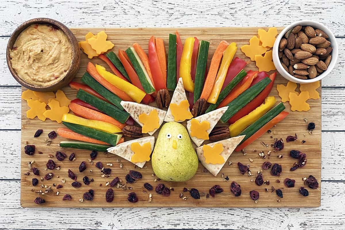Thanksgiving snack board inspired by a turkey,  with vegetables,  almonds, and hummus.