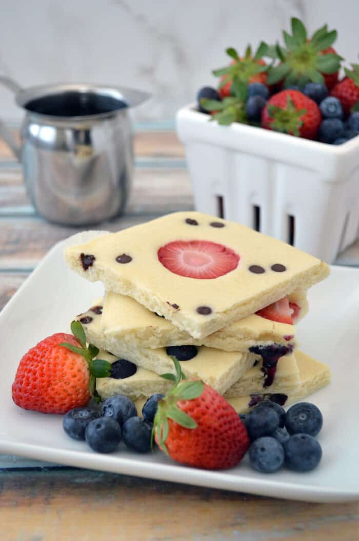 Stacked sheet pan pancakes on plate with fresh fruit.