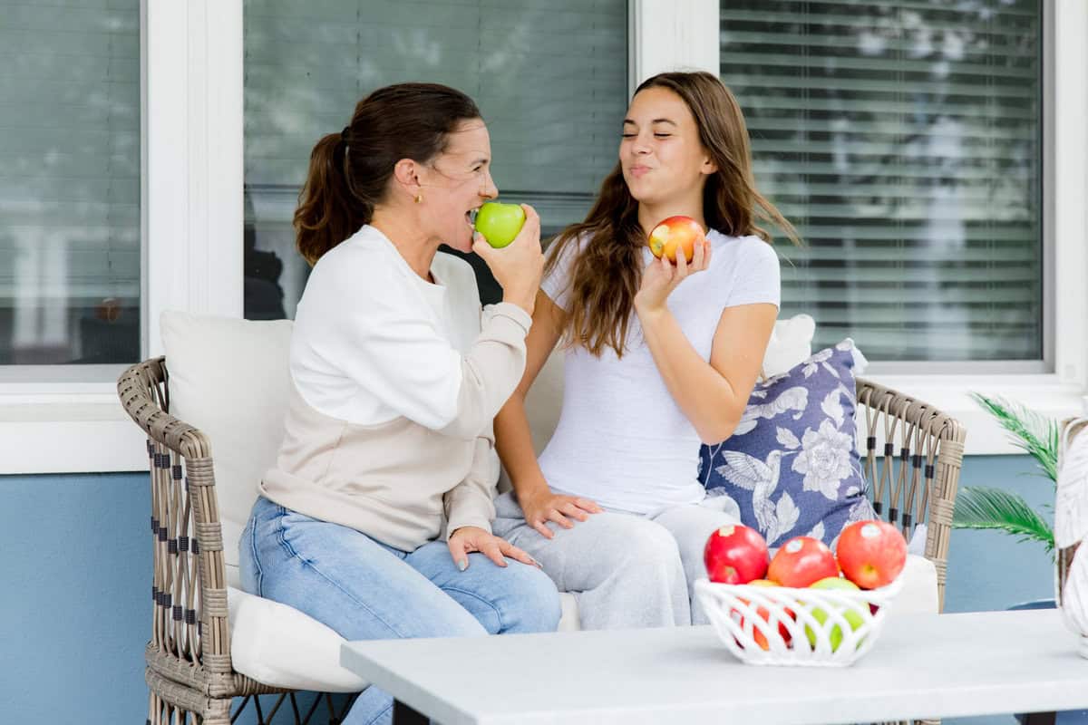 Mom and daughter eating a variety of apples.