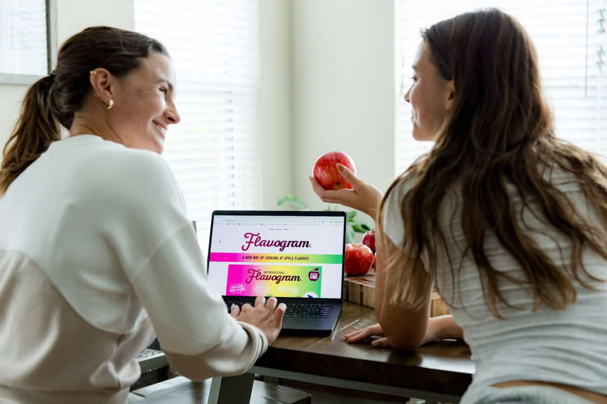 A young lady is showing a red apple to her mom.