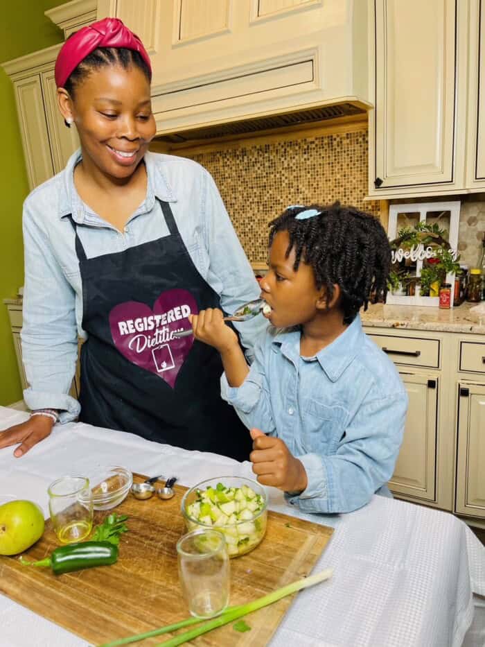 A registered dietitian and her daughter cook and eat together, enhancing wellness.