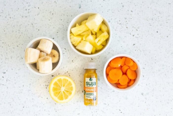 Chopped fruit in white bowls and an energy drink.