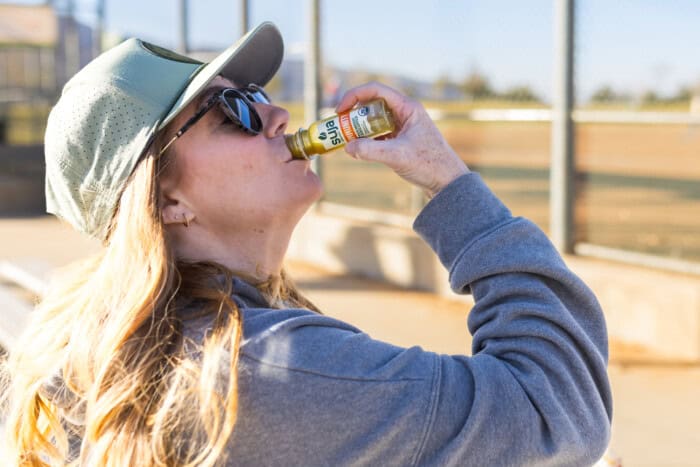 Lady drinking an immunity shot to boost her energy.